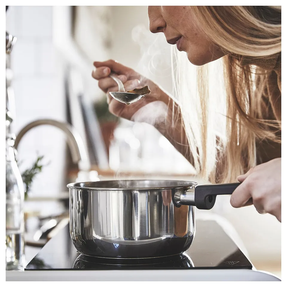 Person cooking in modern kitchen with MIDDAGSMAT saucepan.