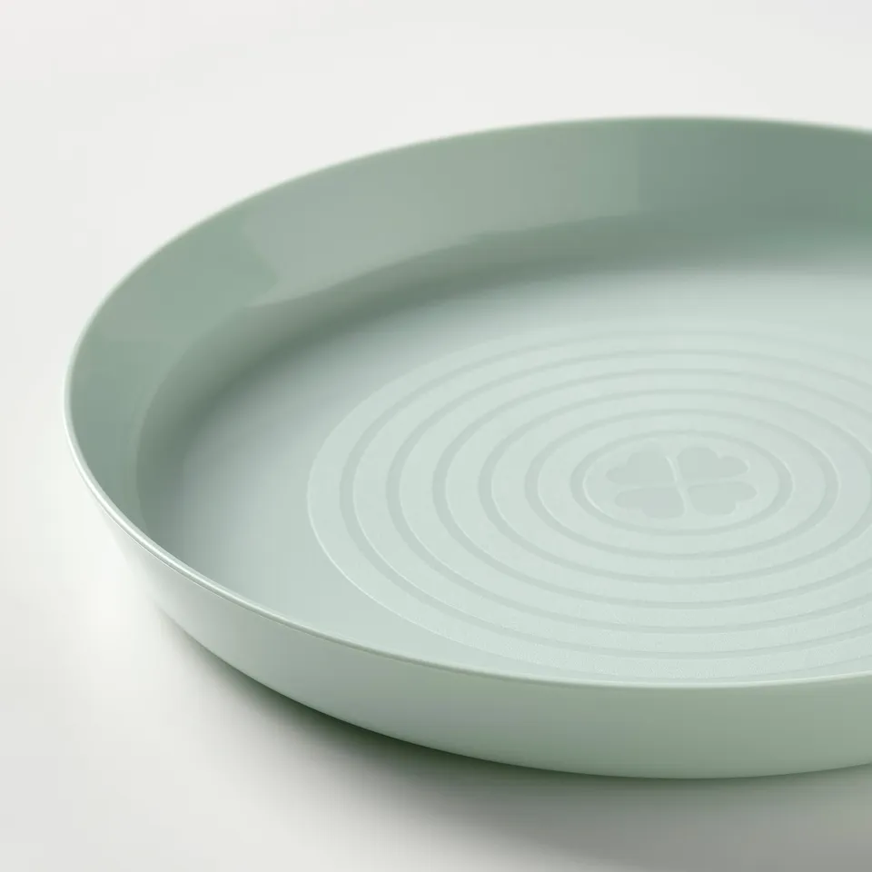 Light green kids plate with curved, smooth edge, set on white surface. Circular ridged pattern inside for grip.