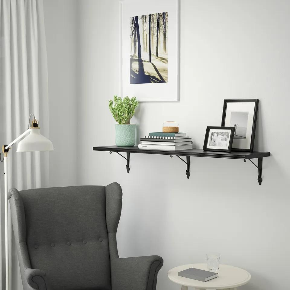 Black BERGSHULT shelf with plants, books, frames, chair, table, artwork, lamp.