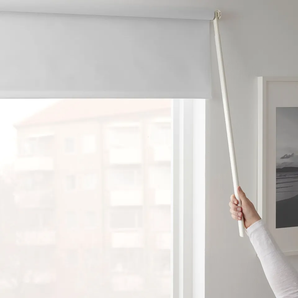 A hand raises a cordless roller blind, blocking light, demonstrating its light-blocking and privacy.