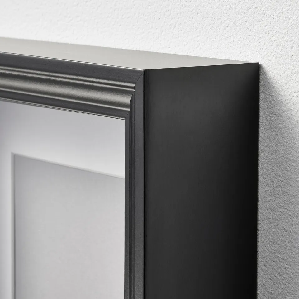 A high-quality VÄSTANHED picture frame with a sleek black finish, mounted on a wall.
