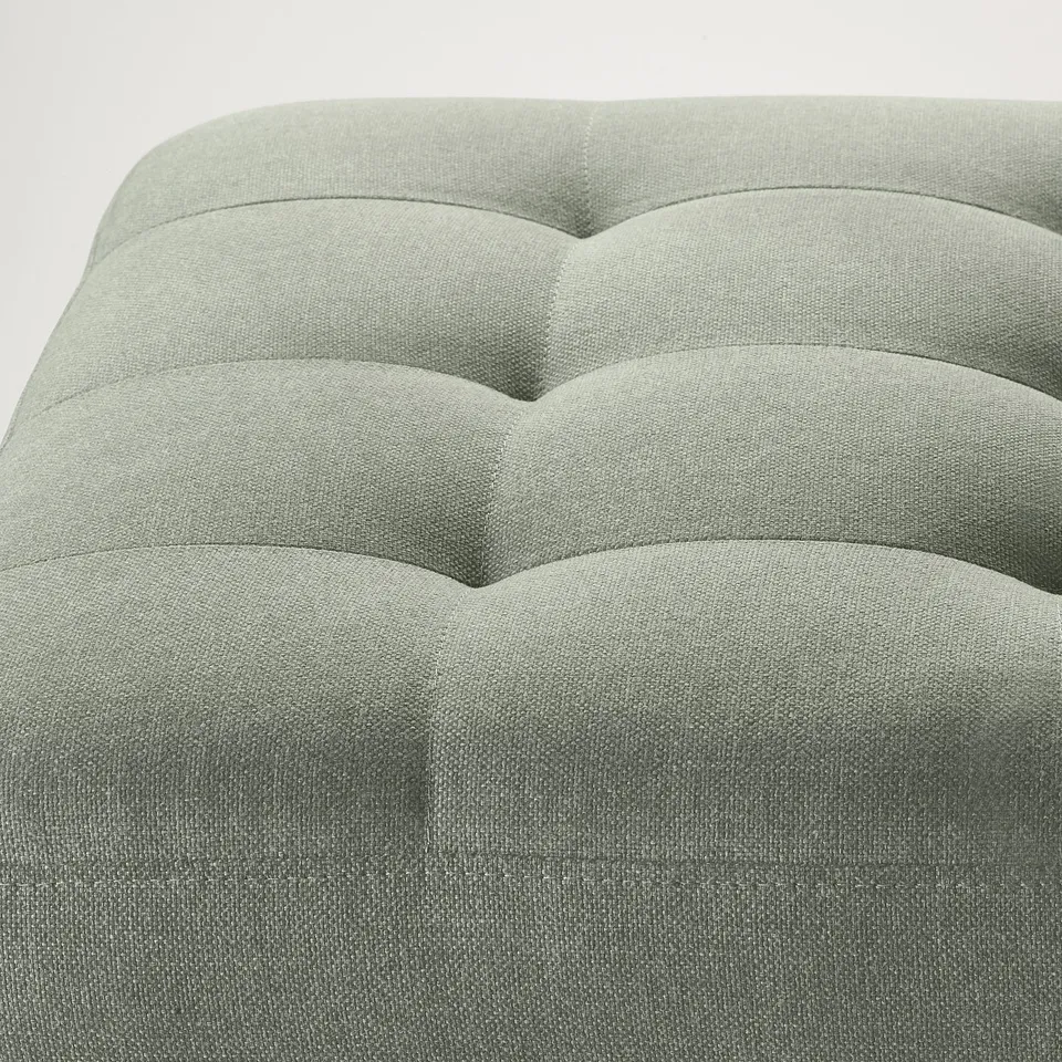 Soft, modern footstool in cloth with wave design, providing comfort and aesthetic appeal.