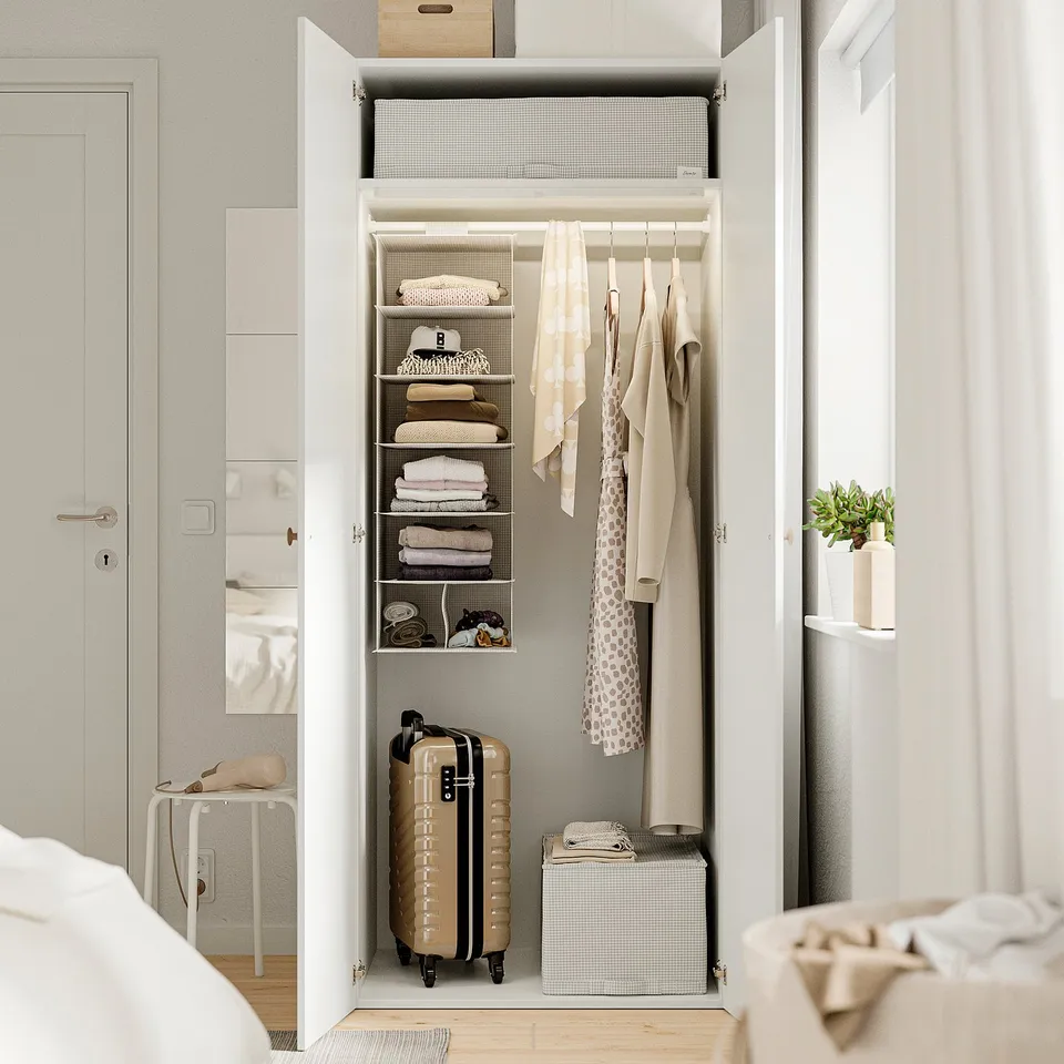 Open closet showing neatly folded clothes, hanging garments, and a suitcase. Storage boxes are stacked under hanging clothes.