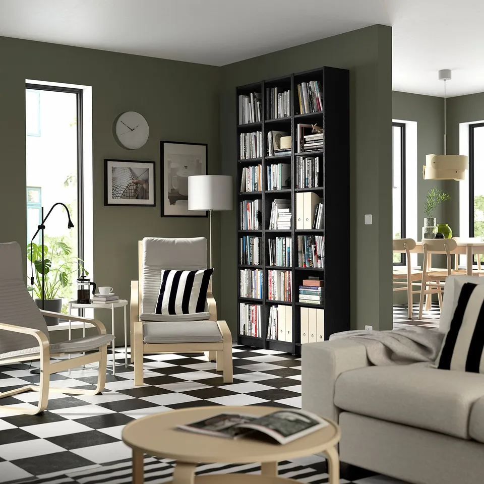 Modern living room with black BILLY bookcase by window. Tall, sleek, packed with books. Checkerboard floor, striped chairs, cosy sofa.