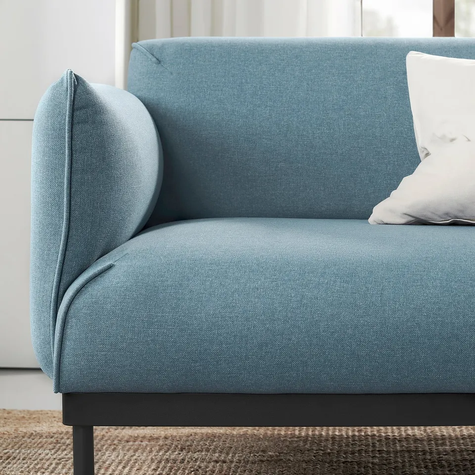A modern bleu ÄPPLARYD sofa with sleek design and cushioned backrest. It a cosy fabric cover and slim metal legs providing a relaxed, stylish look.