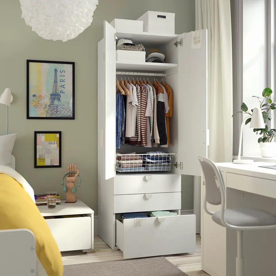 A white wardrobe with a clothing rack, shelves, and drawers in a childs room.