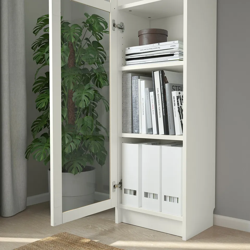 White BILLY bookcase with open doors, containing books and a large plant.
