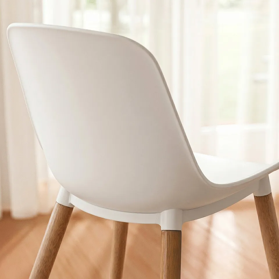 Modern white chair with sleek mould design and wooden legs.