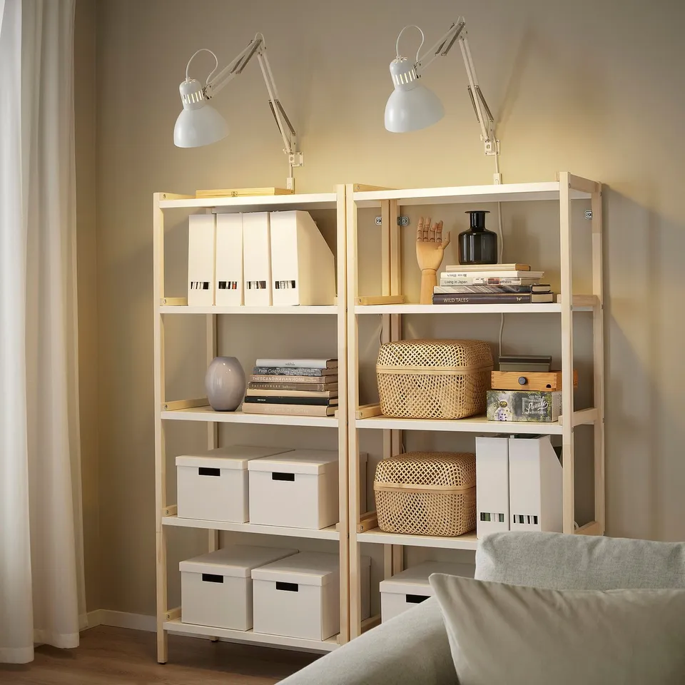 Two lamps on shelf with books, lights on.