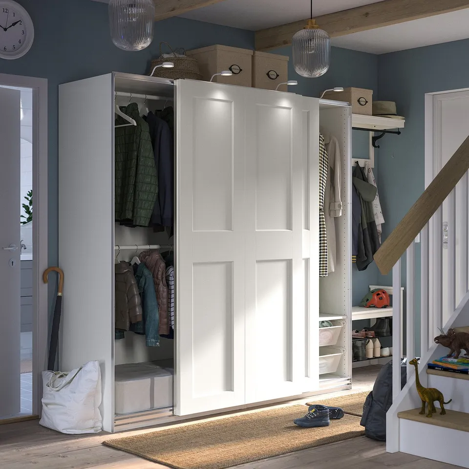Modern hallway with white PAX wardrobe, sliding doors open to reveal clothes and storage.
