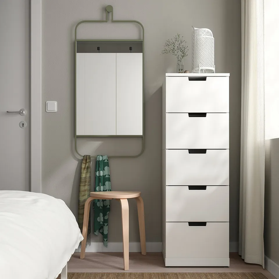 Wall mirror GRANVÅG with green frame reflects room, above white cabinet.