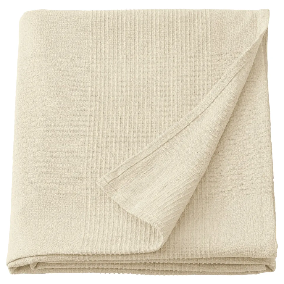 Folded cream-white cotton INDIRA bedspread, textured, for double beds.