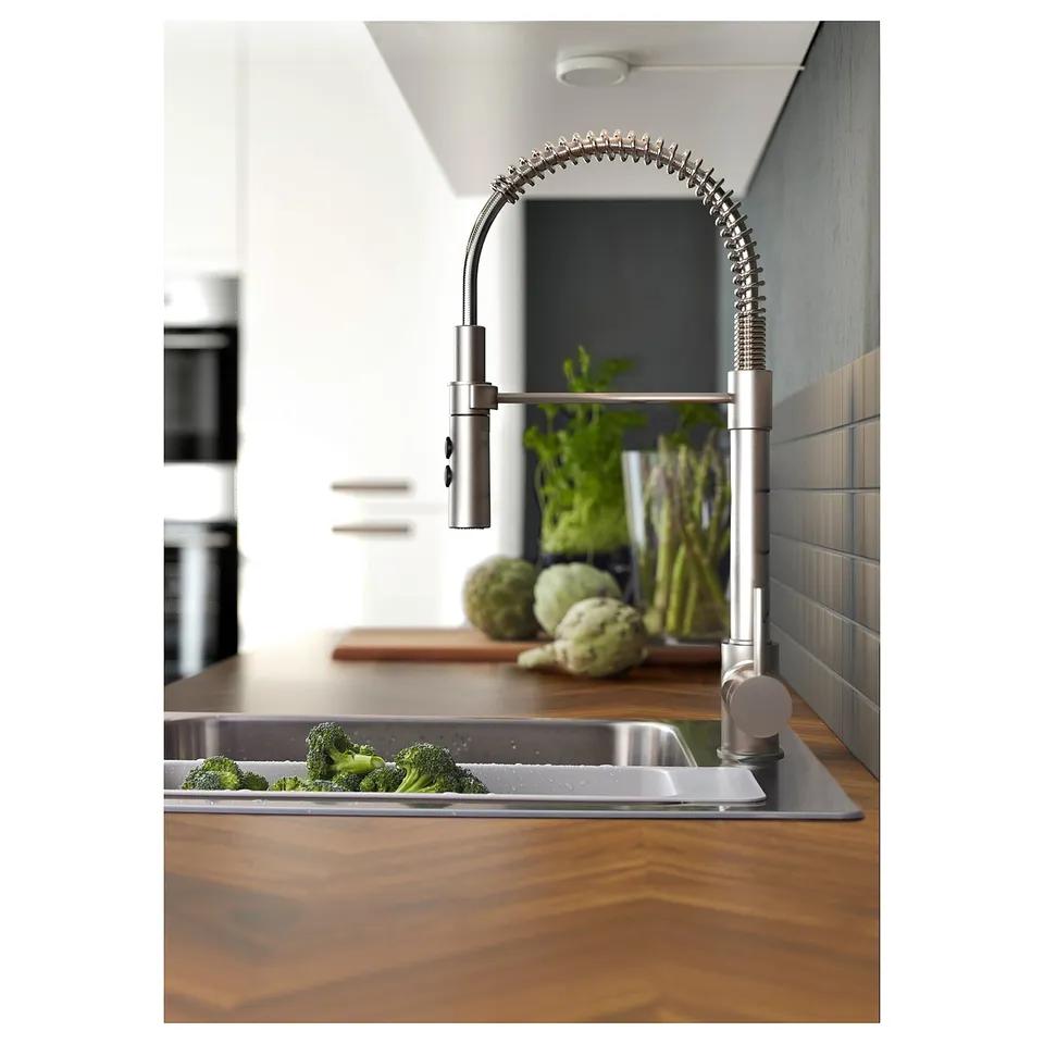 Kitchen scene with BARKABODA walnut wooden counter. Stainless tap, green veggies, tiled wall.