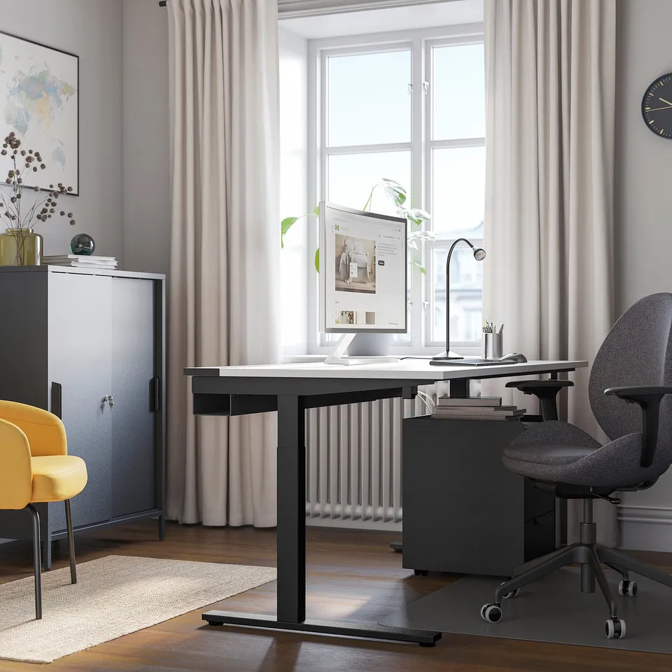 Modern home office with MITTZON height-selectable desk, grey chair, yellow accent chair, and natural light.