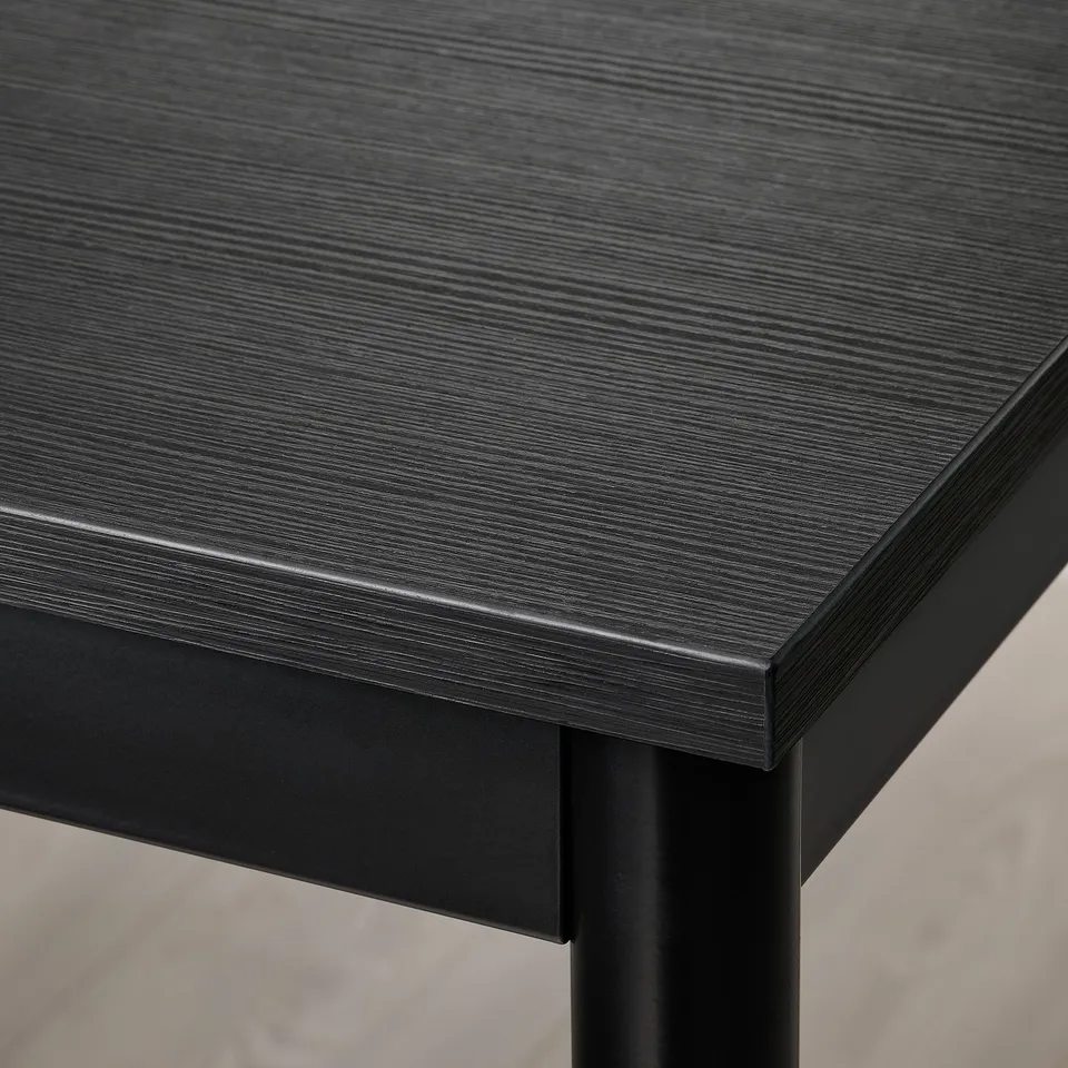 Close-up of a sleek, black sansberg table with smooth melamine top and sturdy metal frame.