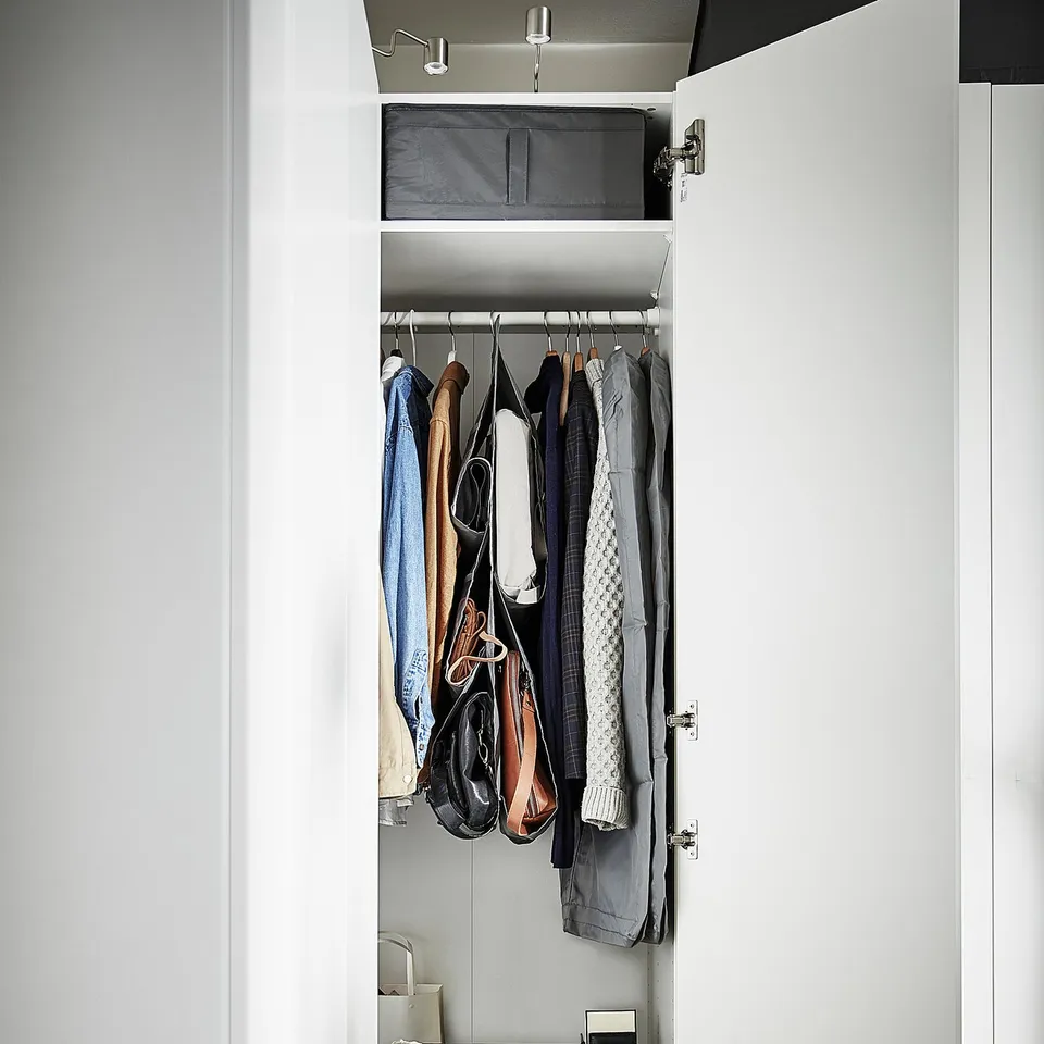 Open closet with organised clothes and accessories. Includes hanging garments and storage boxes.