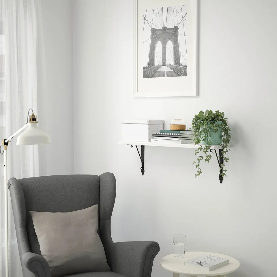 Cosy reading nook with TRANHULT shelf, armchair, lamp, and brooklyn bridge print.