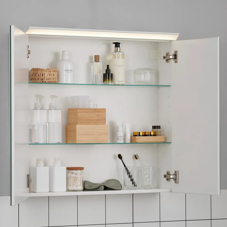 An open, well-lit mirror cabinet displaying organised toiletries on adjustable glass shelves.