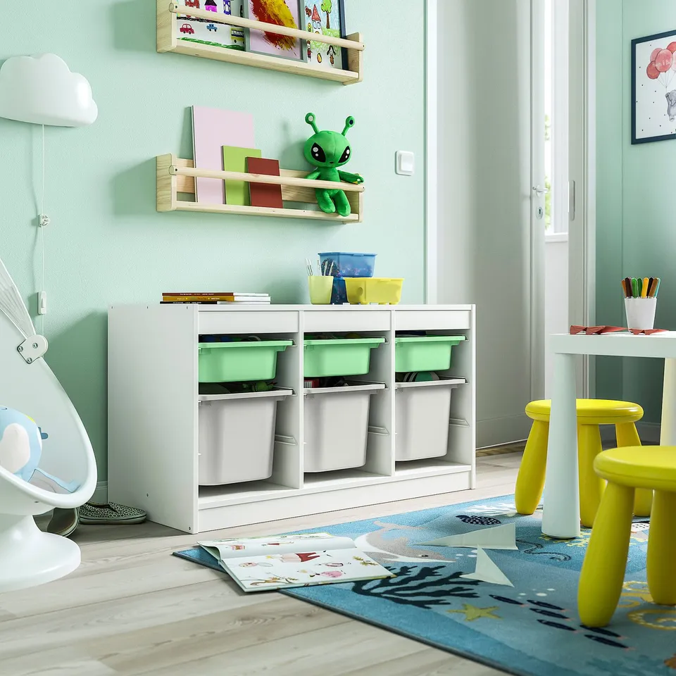 Childrens playroom with TROFAST storage, colourful toys, blue rocket rug, art table, yellow stools.