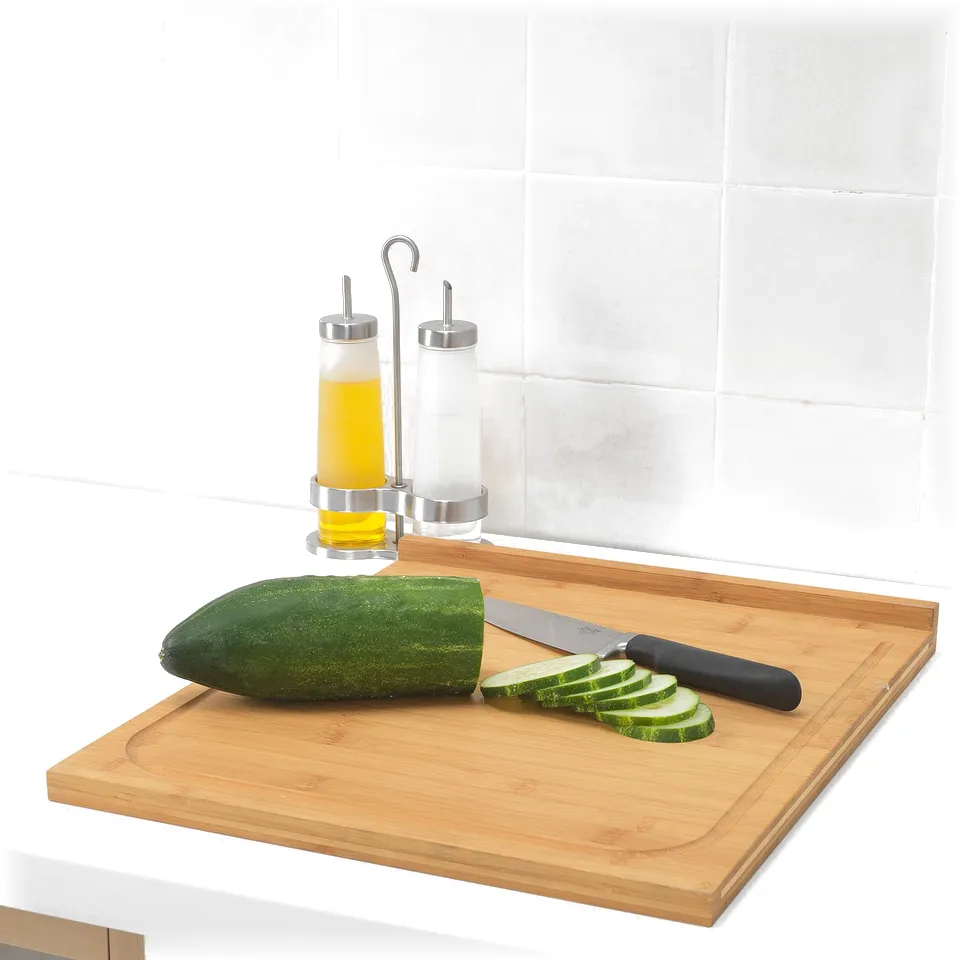 Wooden cutting board with knife and sliced cucumber; oil dispensers behind.