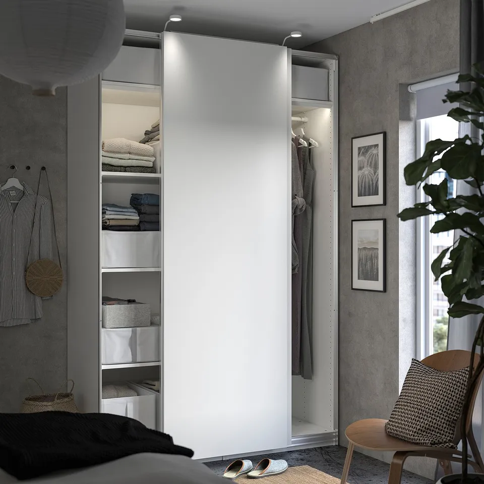 Modern white wardrobe with open shelves, clothes, and lighting.