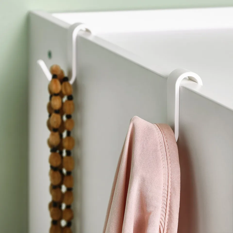 Wall-mounted hooks holding pink item and wooden beads.