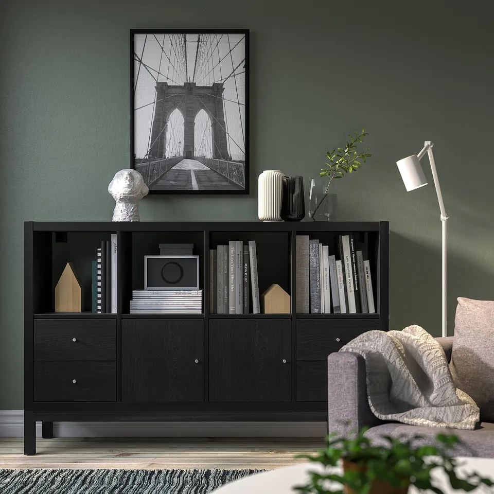 Modern living room with KALLAX shelf, books, decor, brooklyn bridge print, cosy chair, and floor lamp.