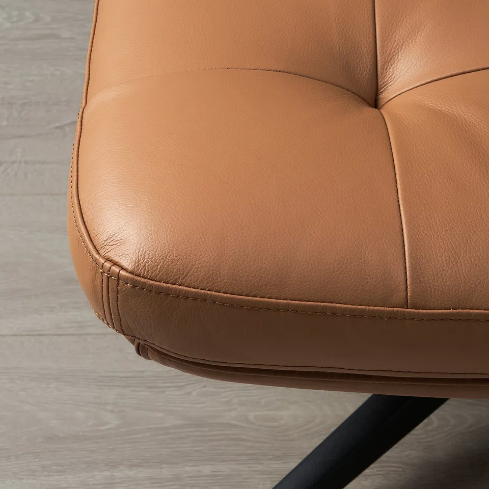 Close-up of smooth, golden-brown leather footstool showcasing quality stitching and comfortable padding.