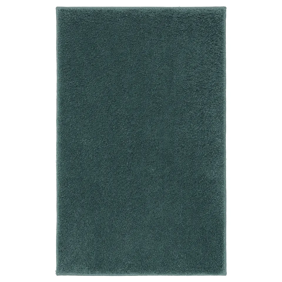The BACKMÅRA bath mat is teal, rectangular, and thick with a textured, soft surface, made from recycled polyester and latex backing.