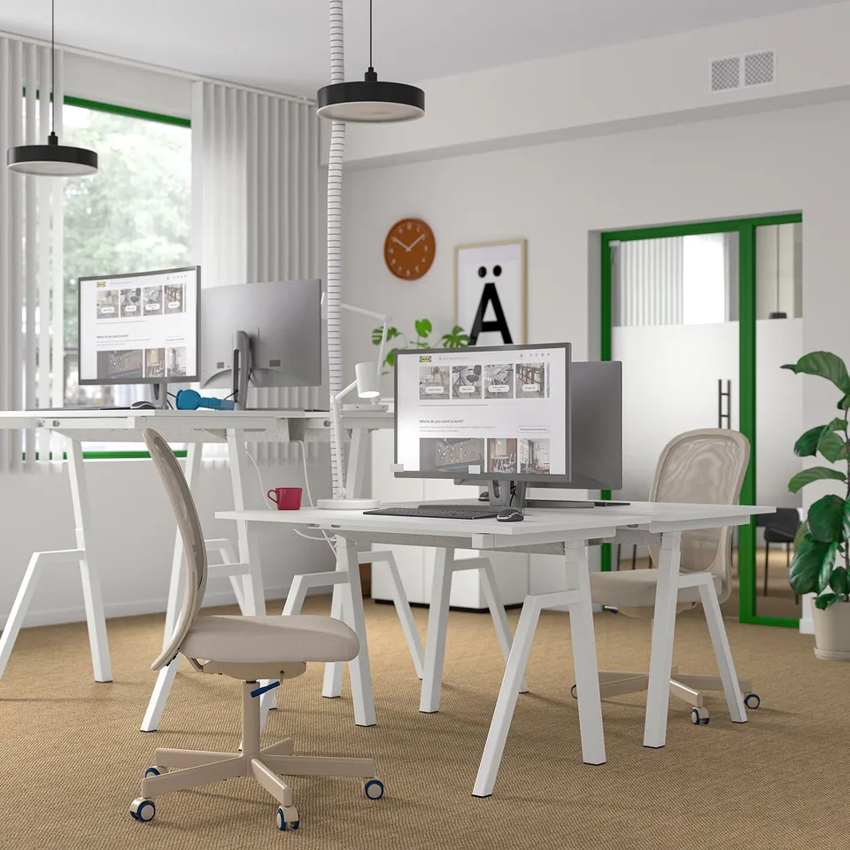 Contemporary office with TROTTEN sit-stand desks, computers, ergonomic chairs, and large windows.