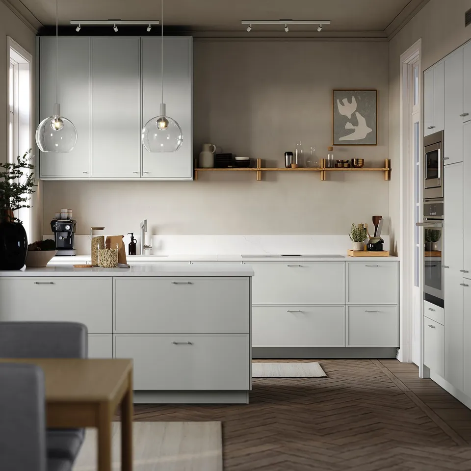 Modern kitchen with white cabinets, wooden floor, hanging lights, and stainless steel appliances. A dining table with blue chairs is visible.