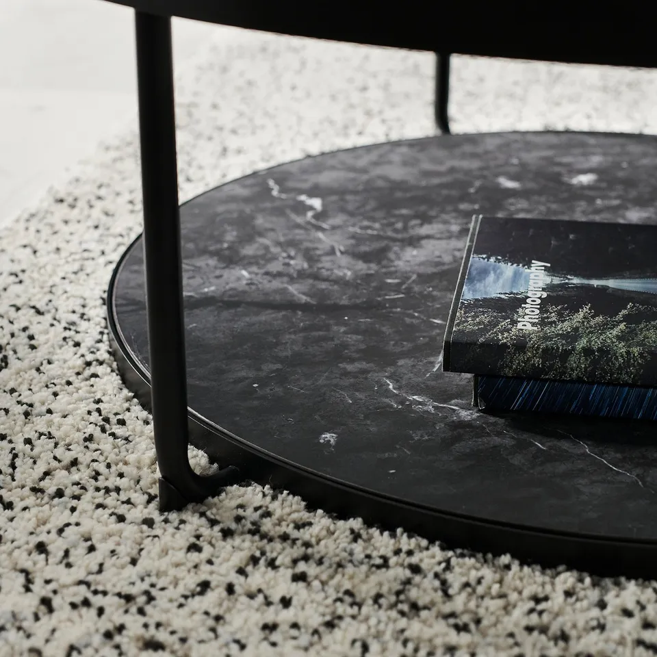 Black round side table with marble-handled display shelf. Glass top, steel legs, modern stylish design.
