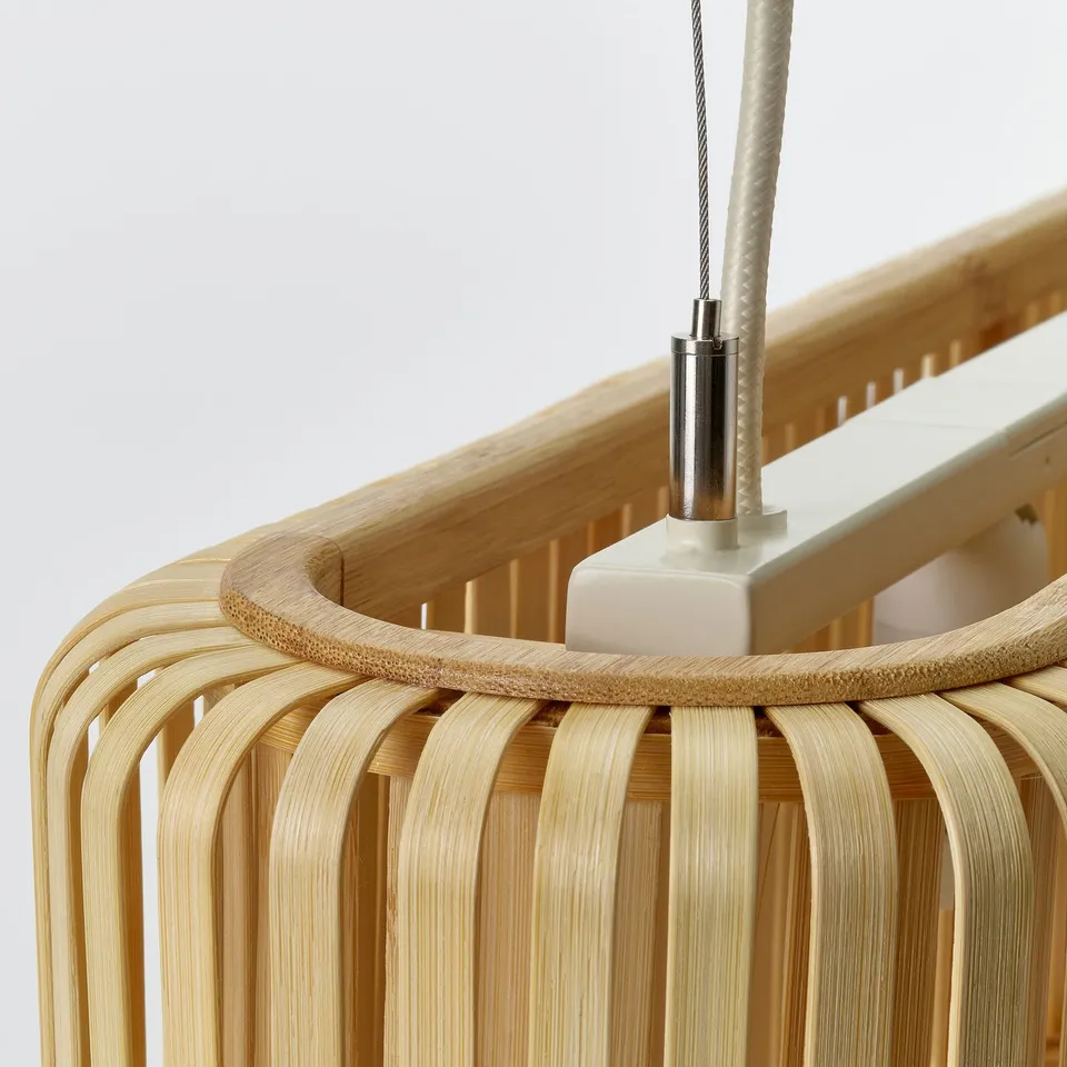 Bamboo pendant lamp shown, hanging from a white ceiling with a stainless steel connector, exhibiting natural wood texture and handcrafted design.