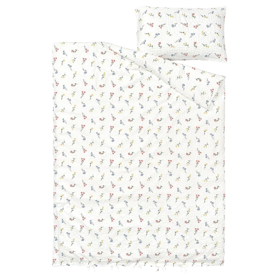 A white PILDVÄRGMAL duvet cover and pillowcase set with a seersucker texture featuring colourful floral patterns.