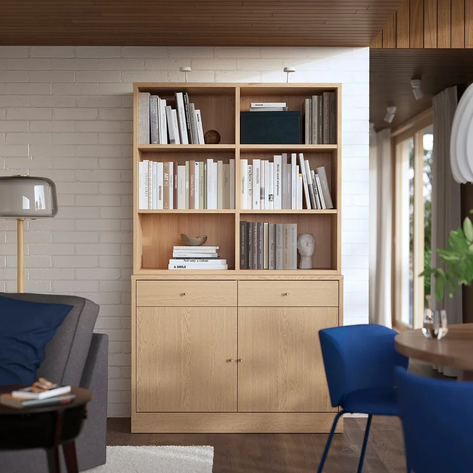 Wooden TONSTAD bookcase against white brick wall with books, grey chair, blue chair.