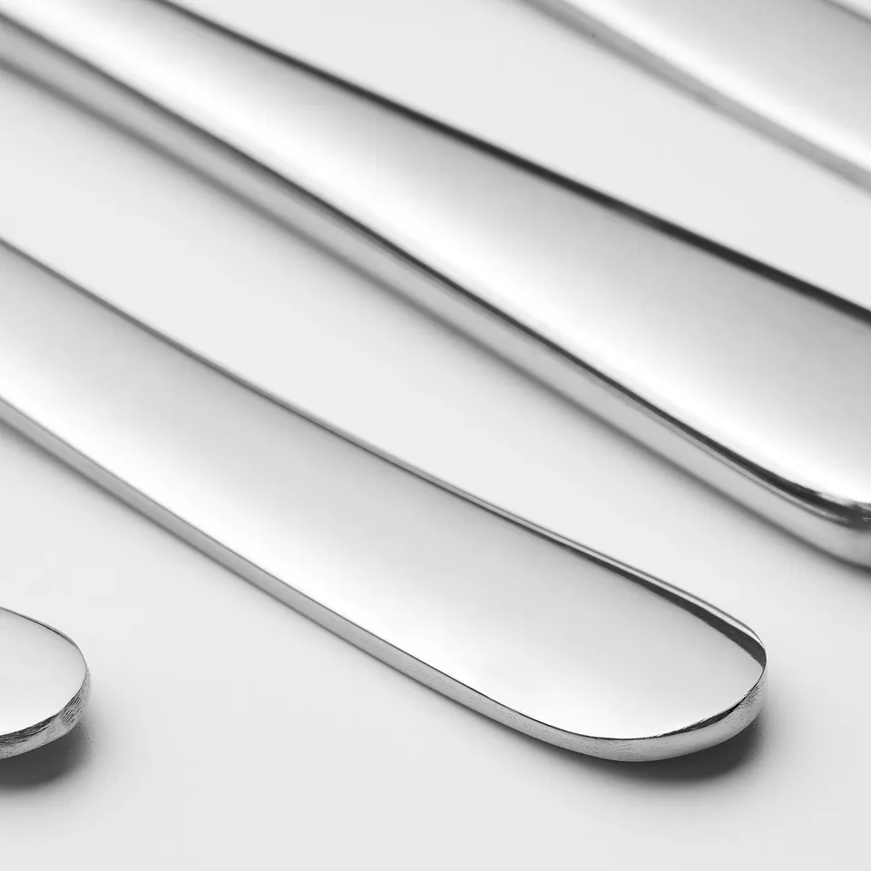 Four metallic utensils on white surface; polished, sleek, arranged neatly.