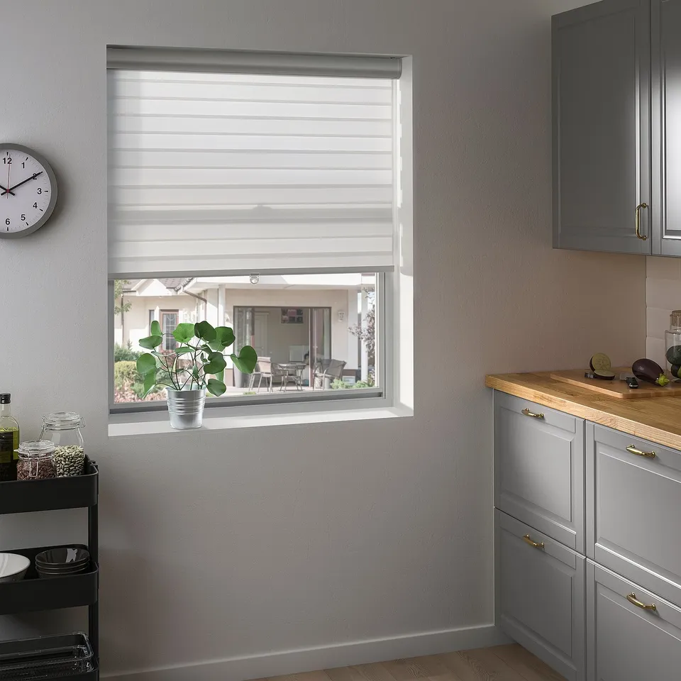 Modern kitchen with TANDLUNDFLY blind, plant, grey cabinets, clock.