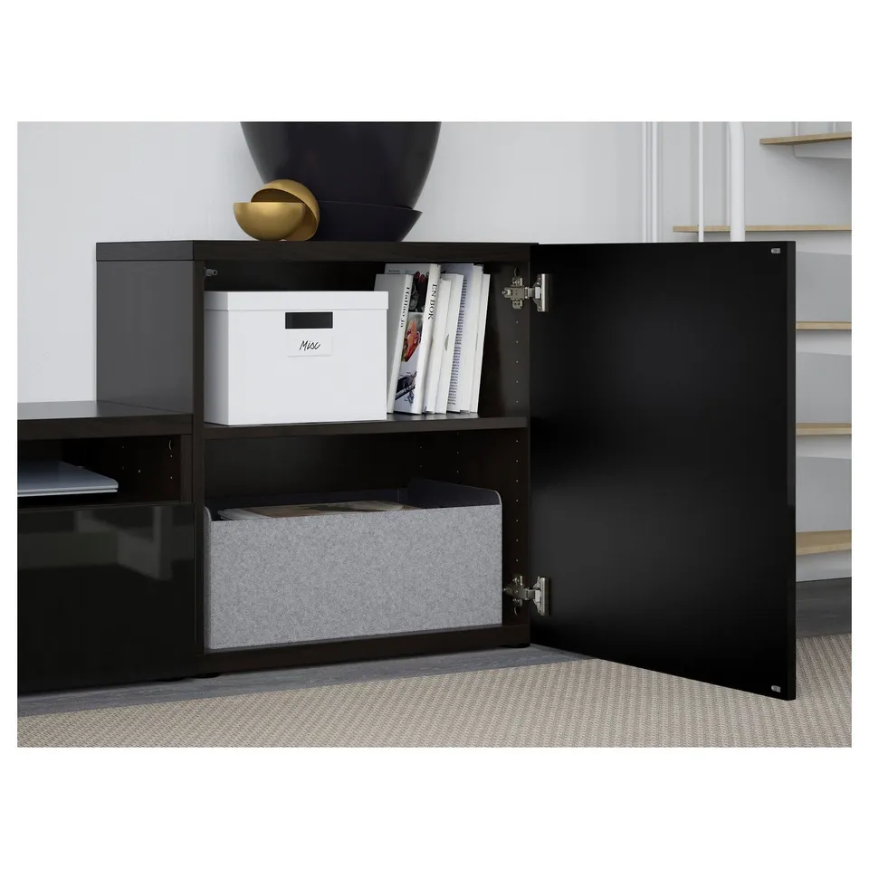 Black BESTÅ tv storage with open doors revealing shelves. Top shelf has white storage box and magazines. Bottom shelf holds grey basket.