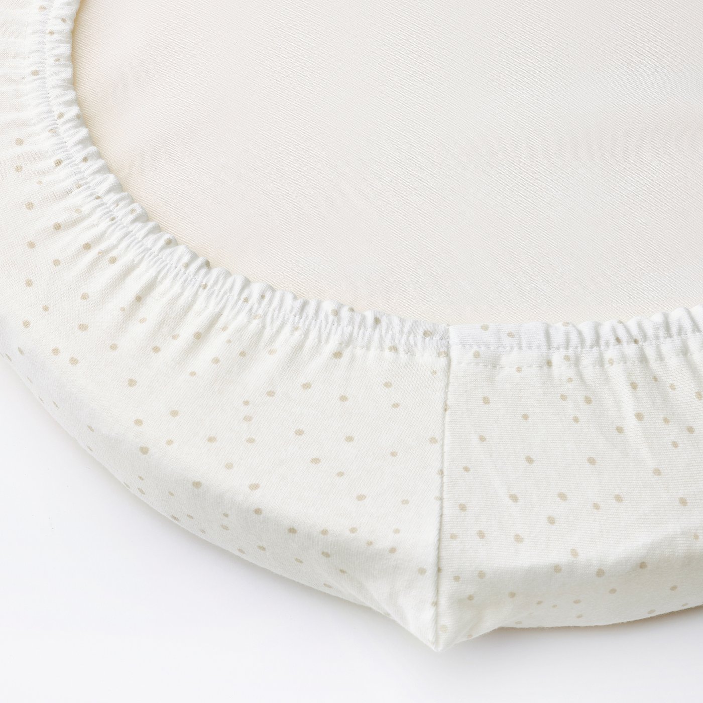 Fitted sheet with elastic edge, securing it in place. Small dots decorate the fabric. Designed for a baby bassinet, ensuring safety and comfort.