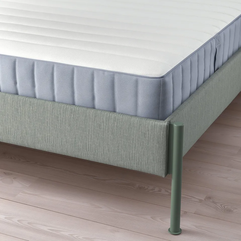 Close-up of TÄLLÅSEN bed frames metal legs, upholstered sides, and supportive mattress.
