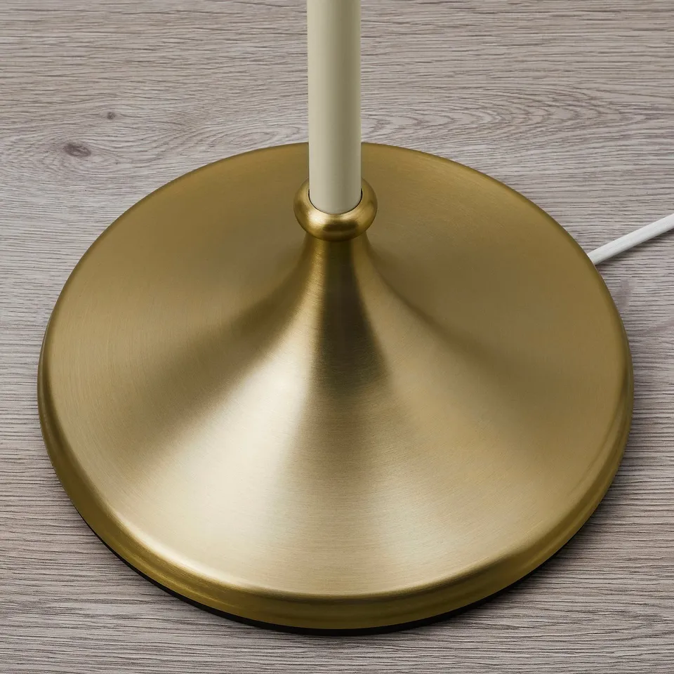 Golden lamp base sits on wood. Sturdy, shiny finish. Simple, elegant design.