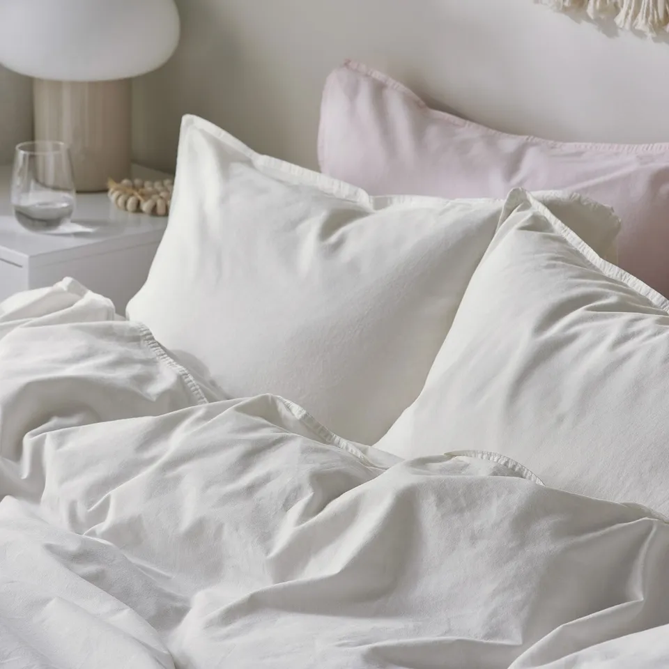 Comfy white bedding with washed cotton, pressed pillows, secure duvet fit.