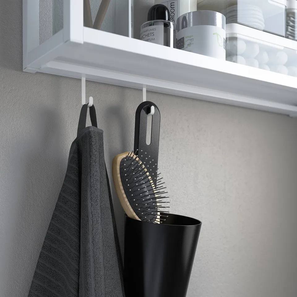 Bathroom shelf with toiletries, towel, and brush organised by ENHET hooks.