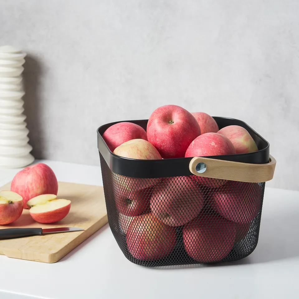 Mesh basket holds apples, ventilates for freshness, sits on countertop.
