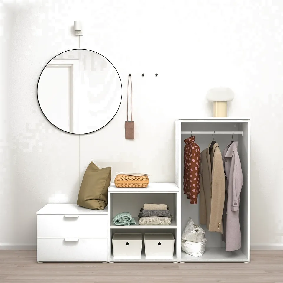 Modern closet with clothes, mirror, and storage boxes. Wardrobe organises up to ceiling, mirror hangs, and storage bins sit on shelves.
