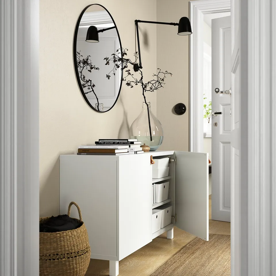 Modern white sideboard with shelves, drawers, mirror, lamps, and vase.