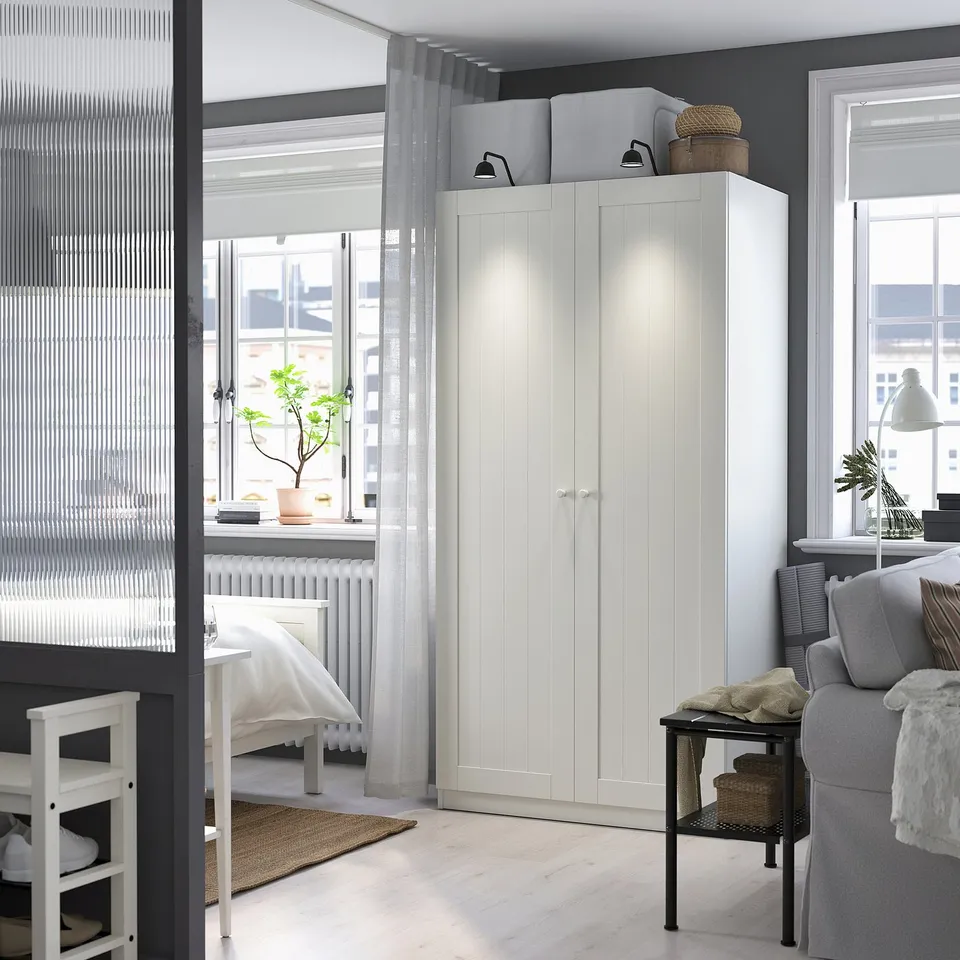 Modern room with a white GULLABERG wardrobe as centrepiece; tall, between windows, with a traditional design fitting pax frame.