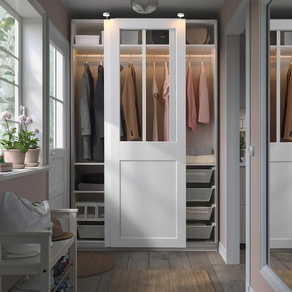 A tall PAX wardrobe with sliding glass doors, displaying clothes and organisers, offering easy access.