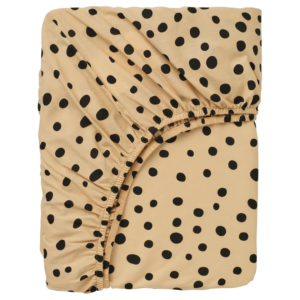 A SANDLÖPARE fitted sheet with a beige and black polka-dot pattern. It has elastic edges for a secure fit.