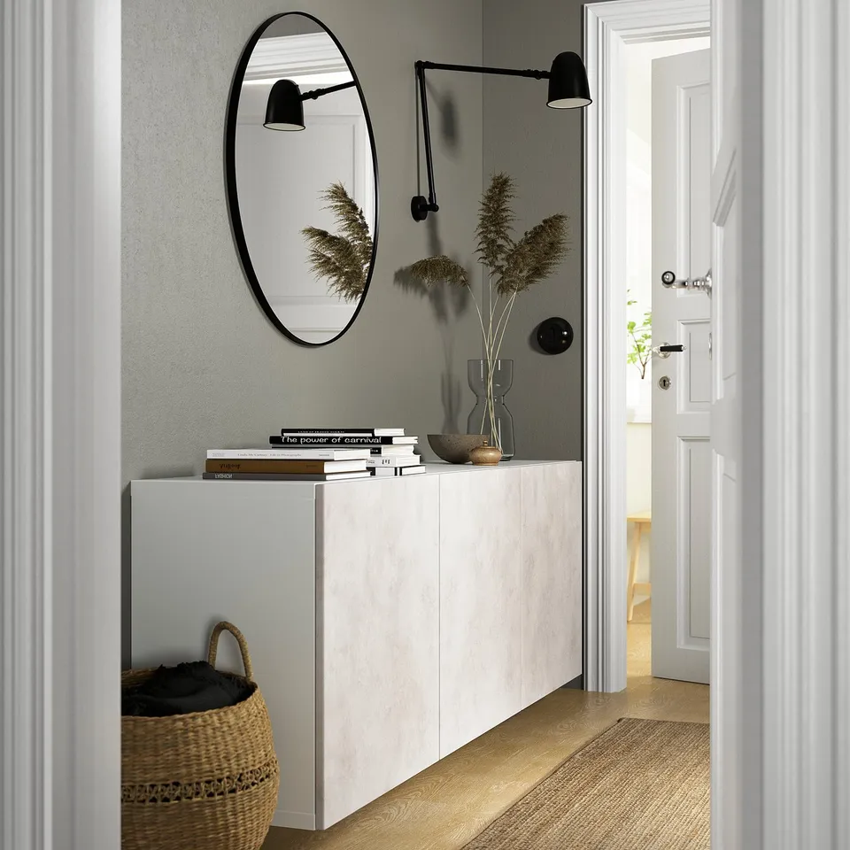 Minimalist entryway: BESTÅ cabinet, mirror, lamps, basket, bright room.
